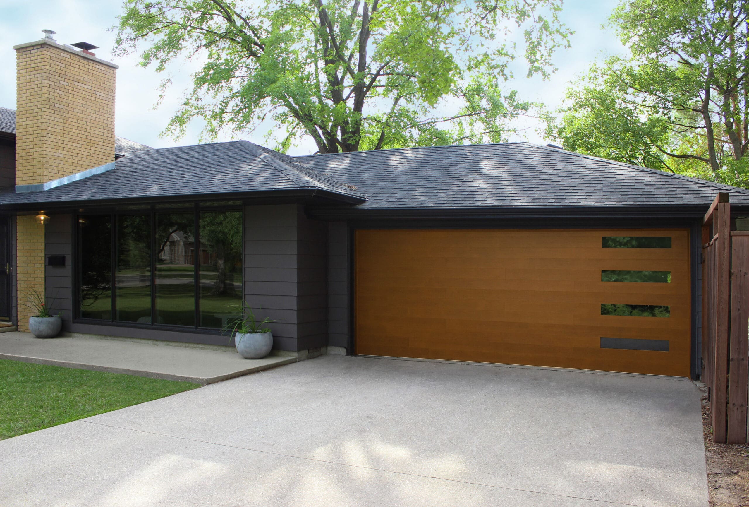 A modern house with a garage, set against a clear blue sky and a neatly trimmed lawn in front
