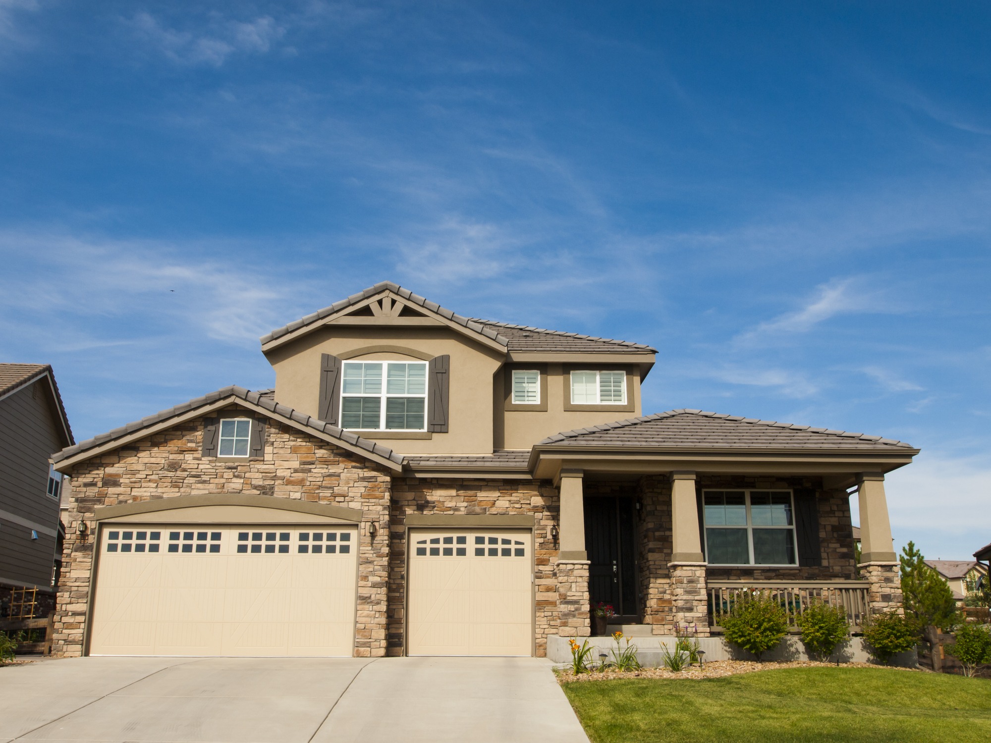 Two-story home with a garage and a driveway, featuring a welcoming entrance and well-maintained landscaping